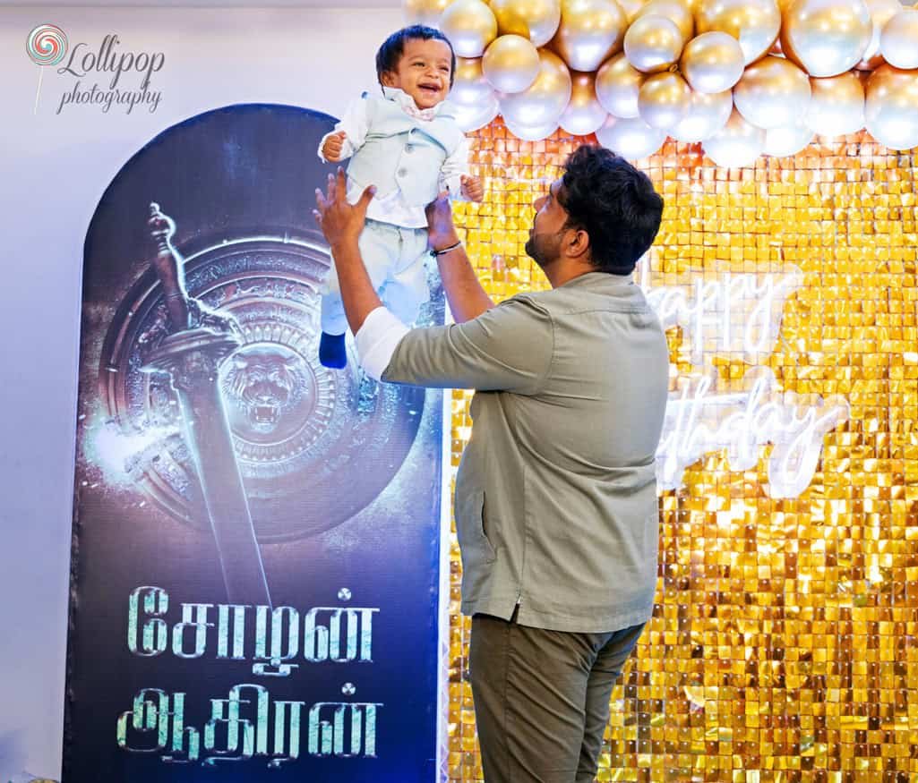 Joyful moment as a father lifts his baby boy in the air, both smiling brightly against a golden birthday backdrop, a special memory captured by Lollipop Photography in Chennai.