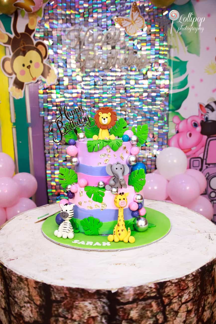 Jungle-themed birthday cake with animal toppers for Sarah's first birthday party, beautifully captured by Lollipop Photography