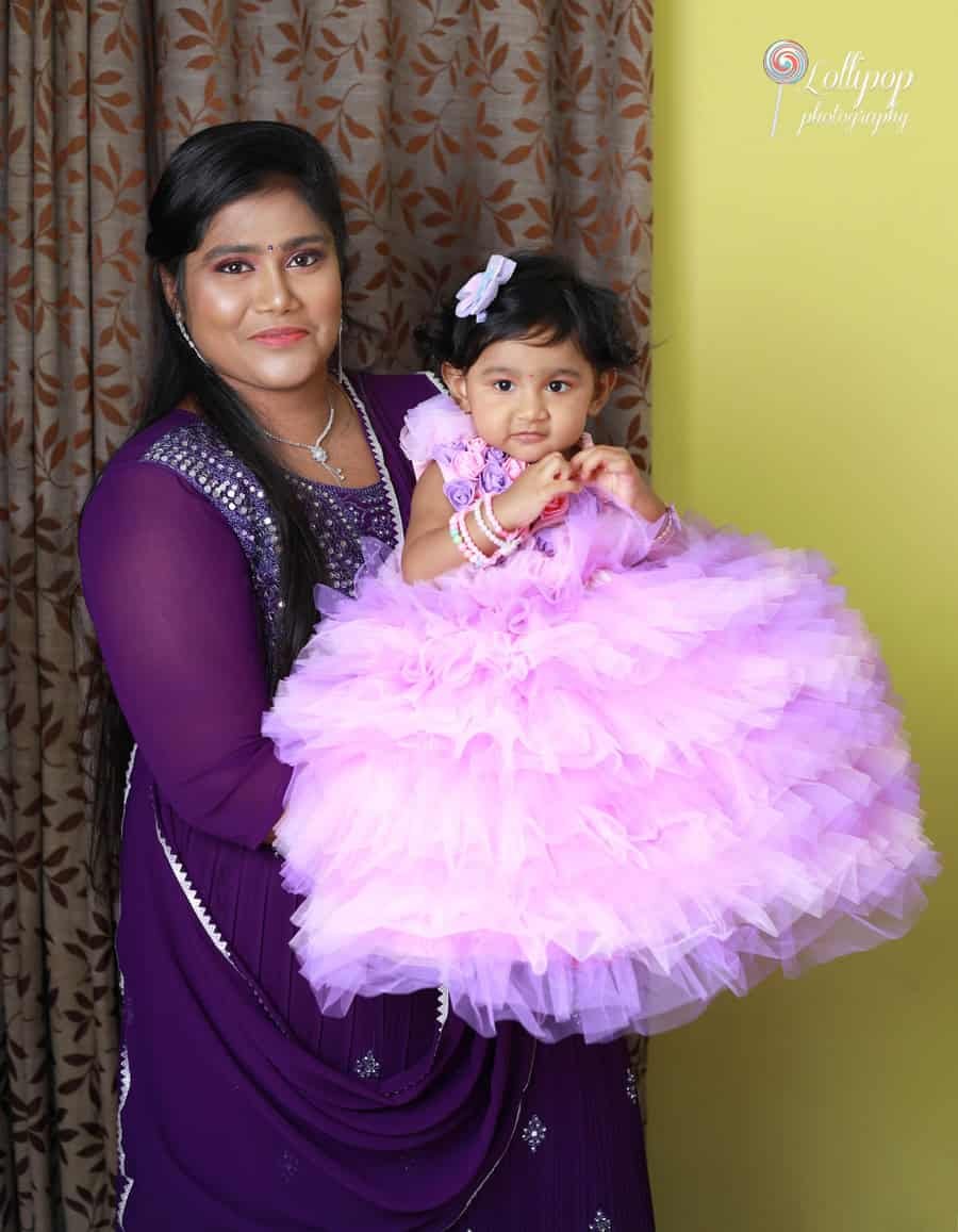 Mother holding her daughter Sarah in a beautiful purple dress, captured during her first birthday photoshoot by Lollipop Photography