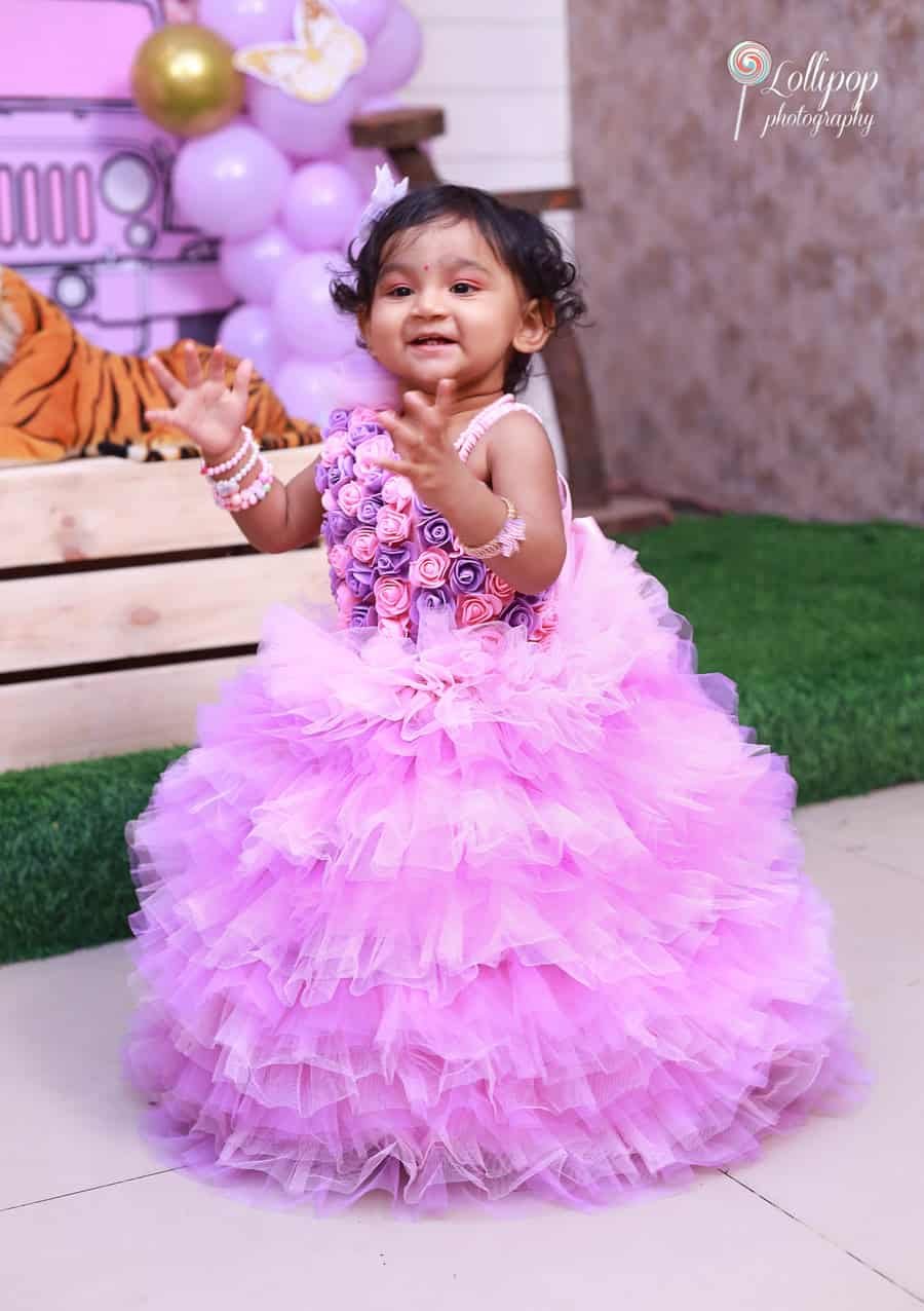 Little Sarah in a floral pink dress enjoying her first birthday celebration, photographed by Lollipop Photography