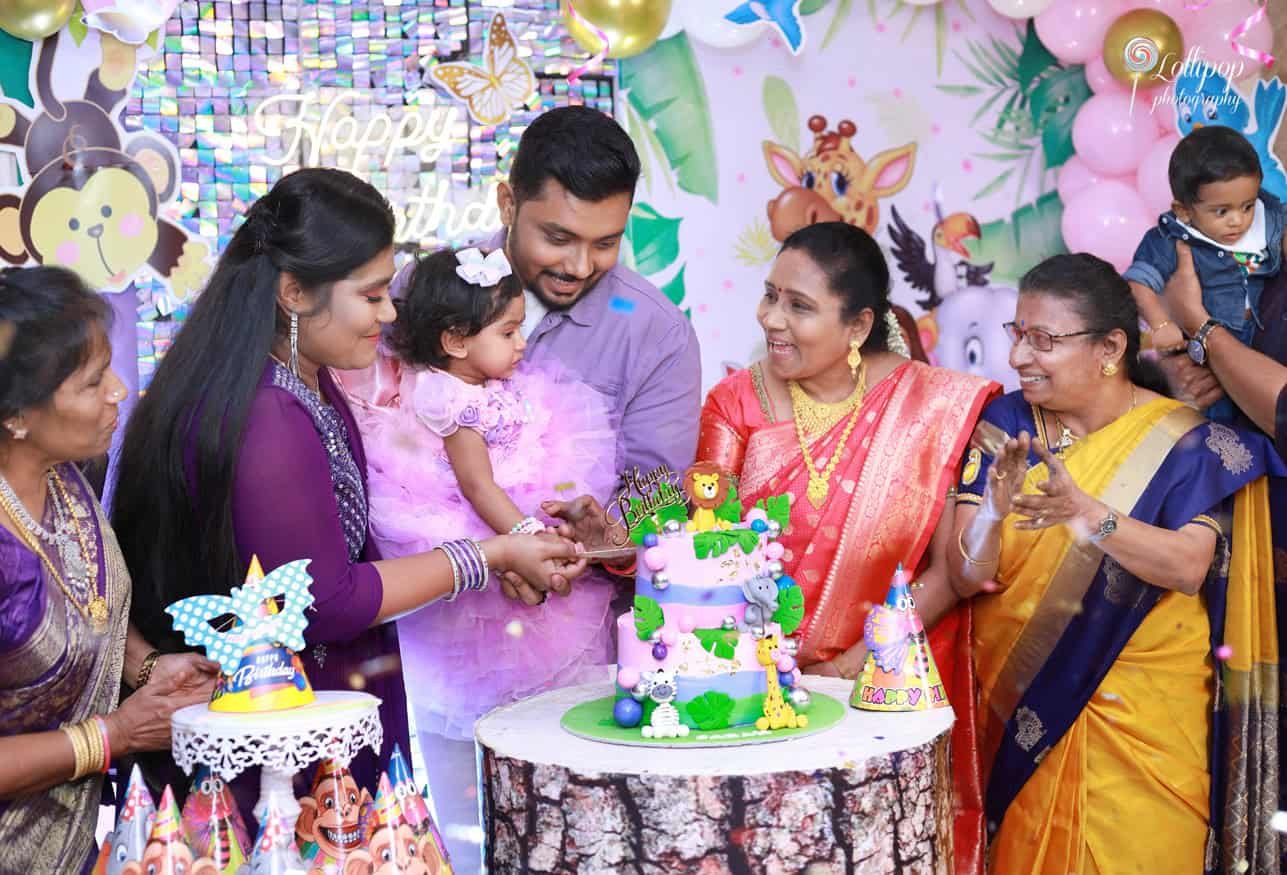 Sarah's parents join her in cutting the colorful birthday cake adorned with animal figurines, captured by Lollipop Photography