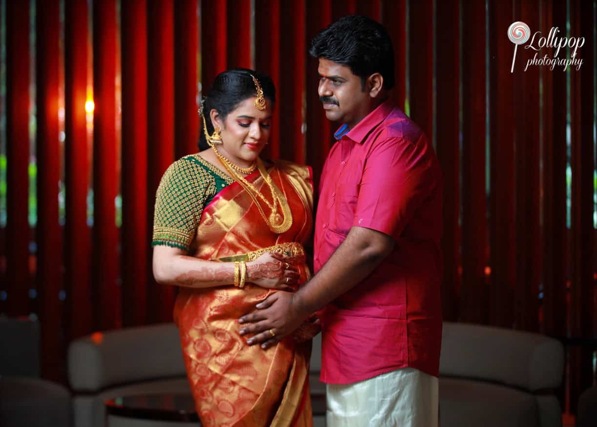 A thoughtful profile of the expectant mother in a golden sari, showcasing her traditional attire and gentle expression, beautifully lit by Lollipop Photography