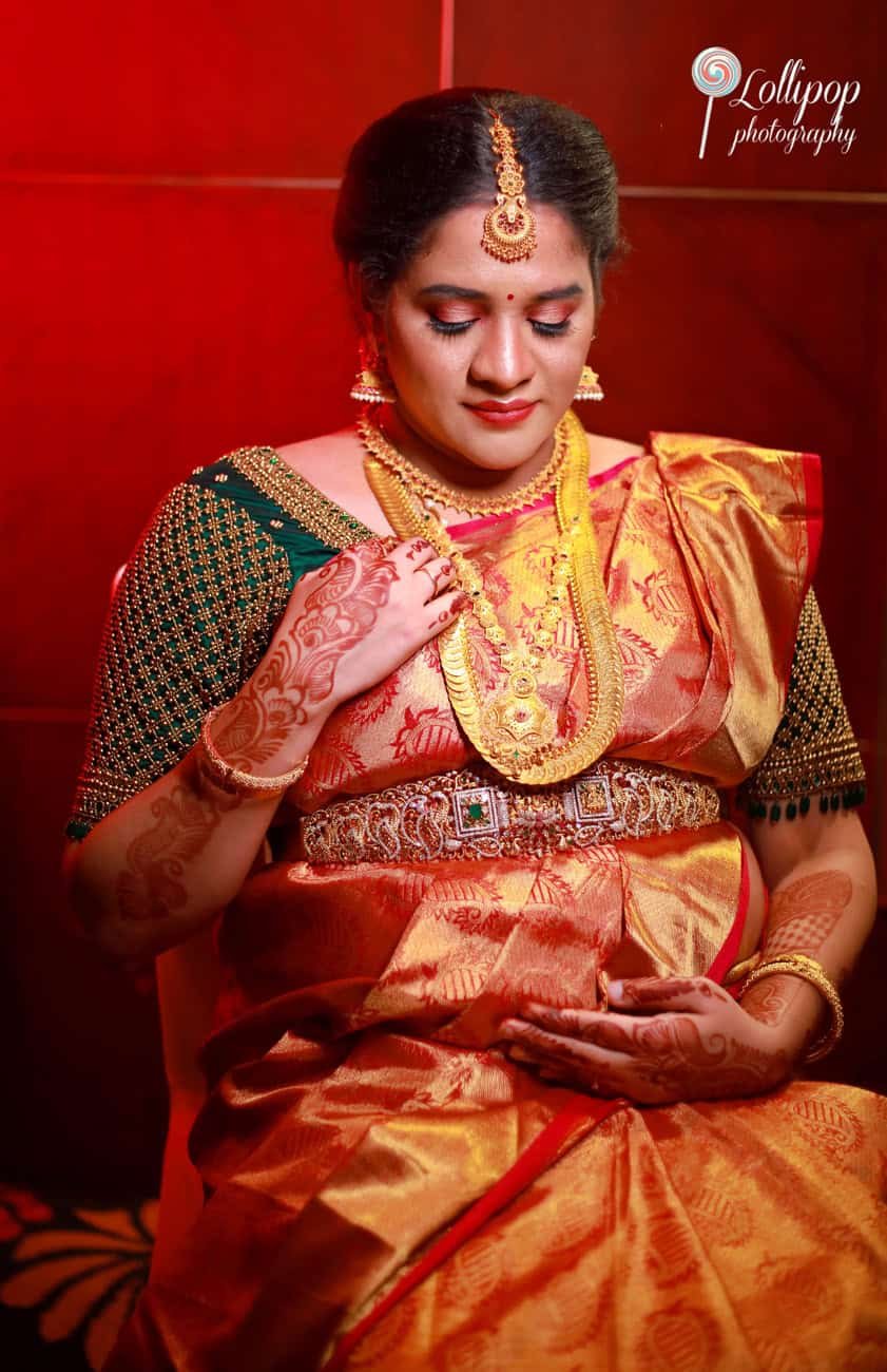 Hemalatha radiates joy in her traditional saree, hands resting on her belly as she celebrates her baby shower, photographed with elegance by Lollipop Photography.