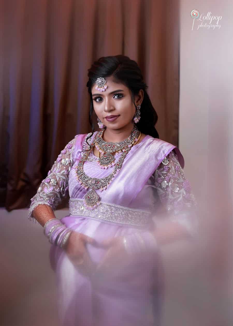 Suganthi looks gracefully at the camera in a lavender saree, showcasing her delicate jewelry and bridal mehendi. A tender moment from her baby shower in Chennai by Lollipop Photography