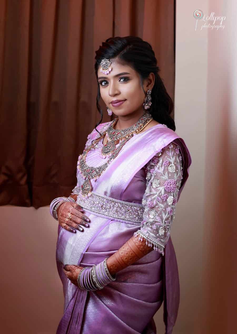 A radiant Suganthi in an elegant lavender saree adorned with intricate jewelry, cradling her baby bump with love. Captured by Lollipop Photography, Chennai